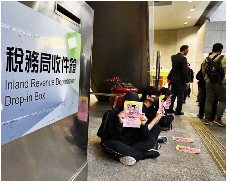 有黑衣人在大樓大堂內靜坐。