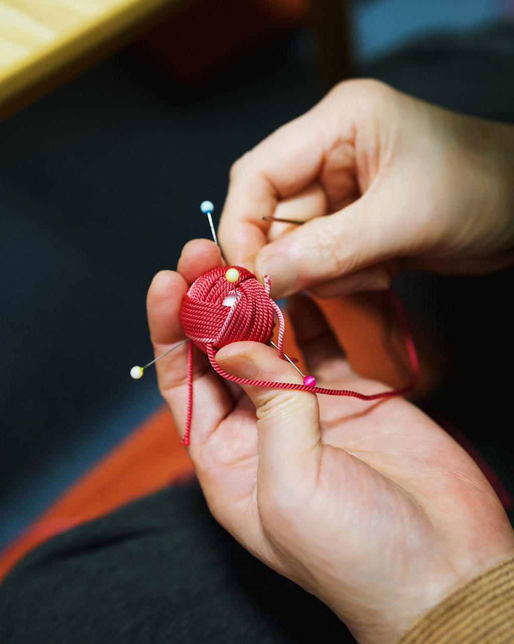中森編織工坊工匠將珍貴絲線纏裹在撞色珠扣上，打造出生動的對稱圖案。