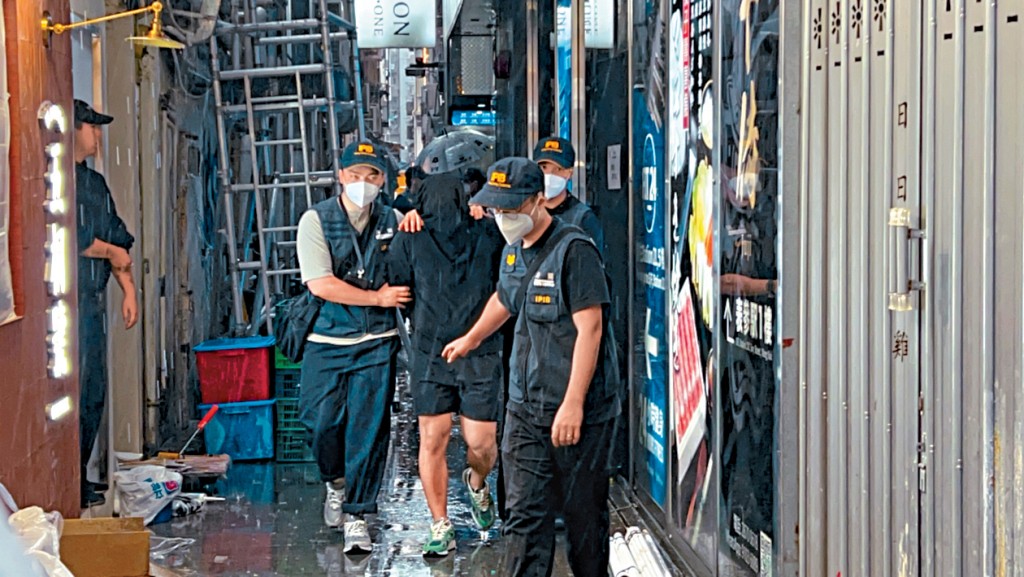 被捕职员黑布蒙头由关员押走。小图为海关版权及商标调查科不良营商手法调查课第二组指挥官庄启成。