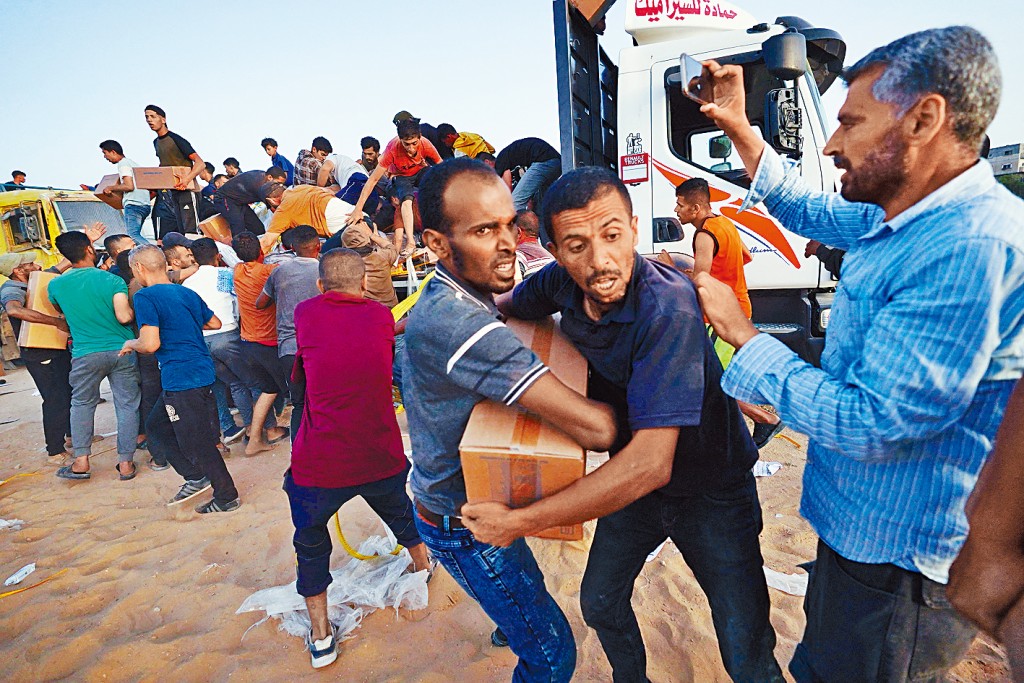 貨車從美國在加沙中部海岸建造的臨時碼頭運來物資，巴人蜂擁爭奪。