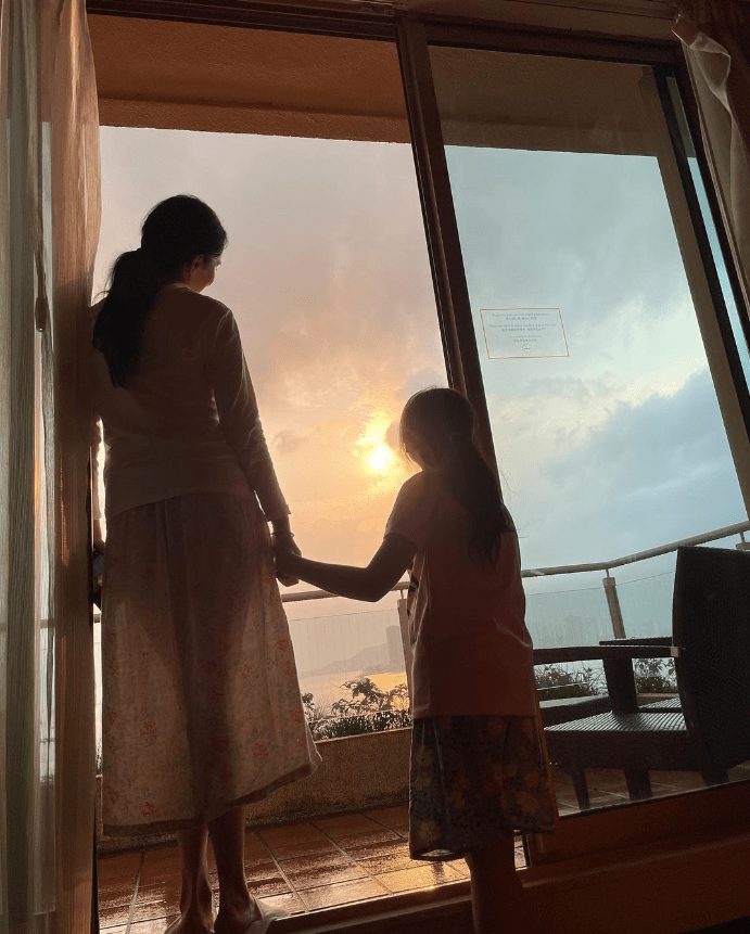 郭羨妮拖著女兒趁日落時拍照，她所穿的透視裙若隱若現。