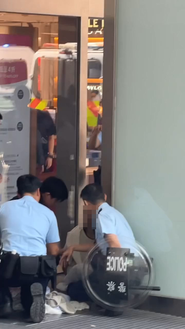 女子被制服後一度坐在地上,雙手被鎖上手銬。 女子被制服後一度坐在地上,雙手被鎖上手銬。