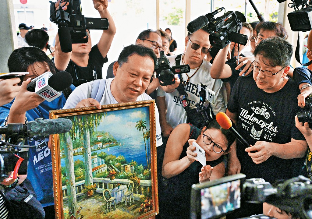 居民鍾先生執拾了掛在寓所牆上的心儀畫作。