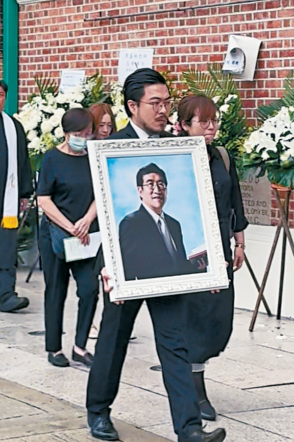長子李啟旻神情哀傷捧着父親遺像，長女李嘉欣哭成淚人，而李師母則低頭跟在身後。