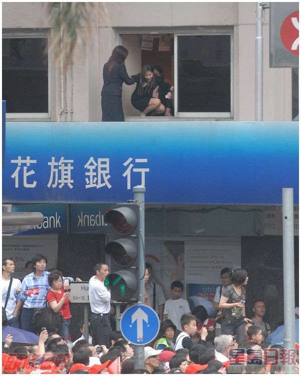 有员工爬出商场簷篷顶观看奥运。资料图片