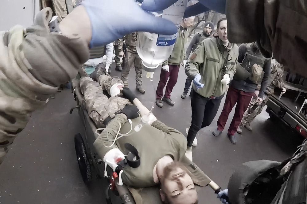 女軍醫用隨身攝錄機拍攝救治傷兵的實況。AP