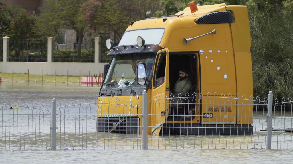 杜拜罕見暴雨，一輛拖頭停在水中央，男子無奈被困車上。 美聯社