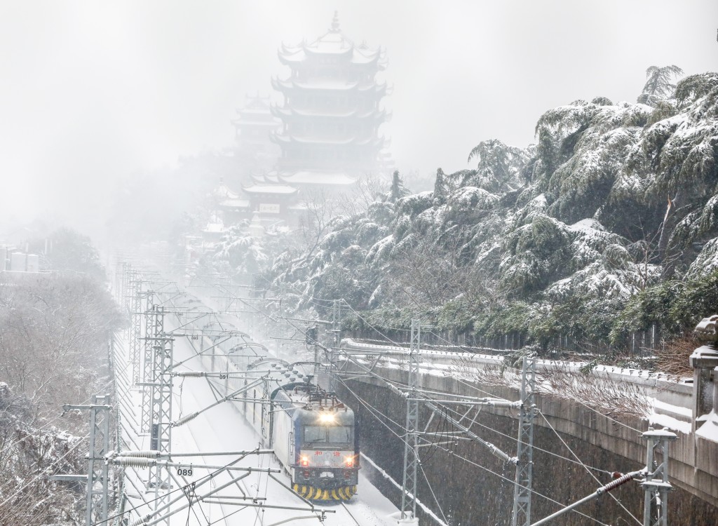 湖北武汉降雪天气持续，内燃机车列车雪中从武汉黄鹤楼旁驶过。