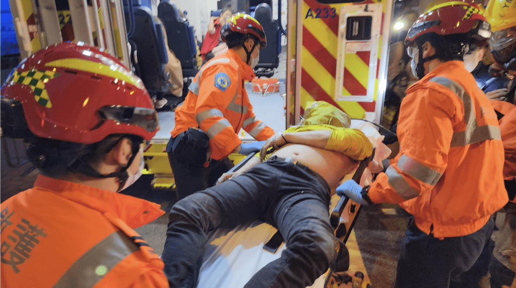 救護人員將昏迷男子由擔架床送院。黎志偉攝