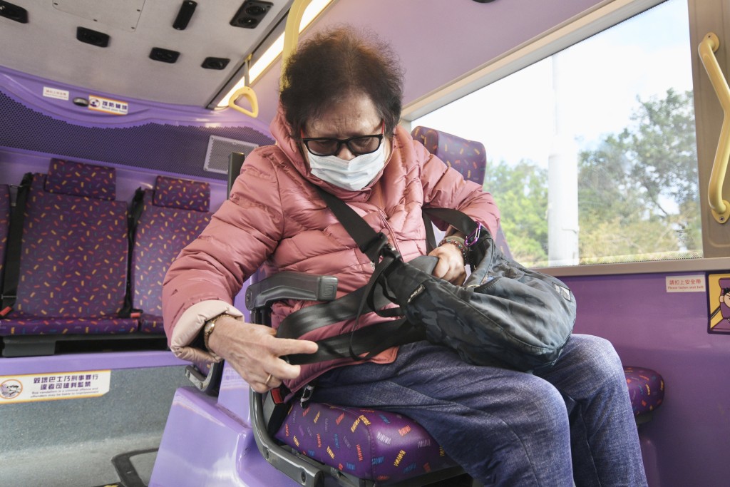 金婆婆嘗試扣上安全帶，惟拉錯旁邊座位、又因身上的「斜孭袋」顯得吃力，甚至一度不夠力拉出安全帶。