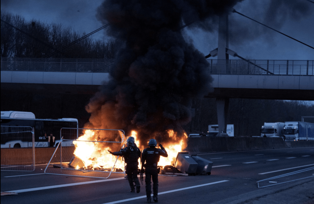 在法國雷恩，於抗議退休制度改革的抗議活動中，警察在高速公路上一個燃燒中的路障旁工作。這張圖片來自社交媒體。（路透社）