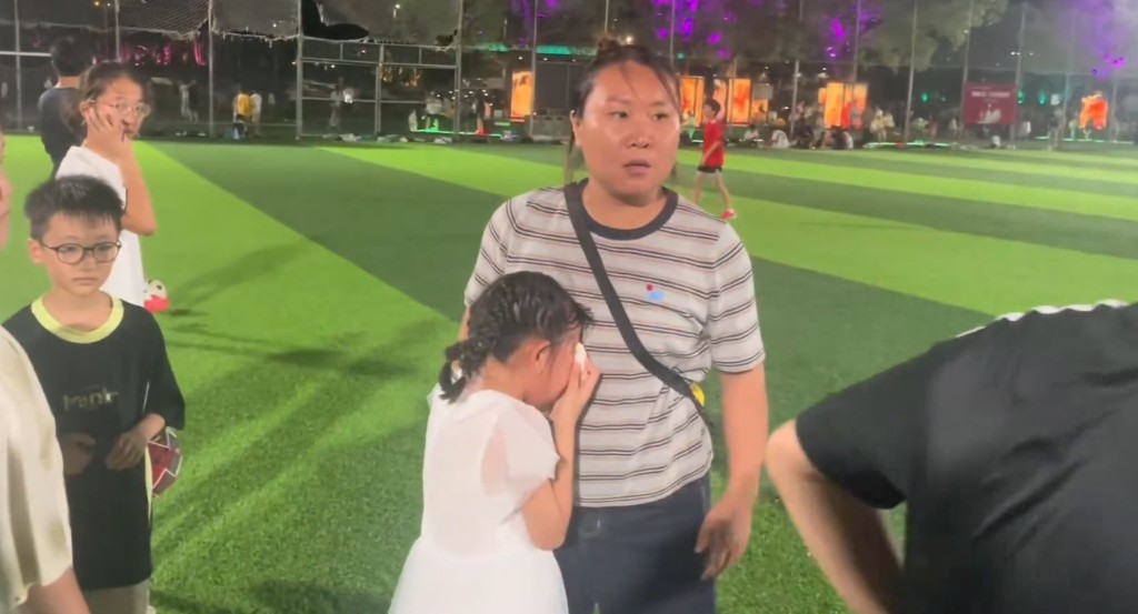 宝妈不顾危险带孩子穿越足球场，女儿被球踢中即情绪失控拒绝离开。
