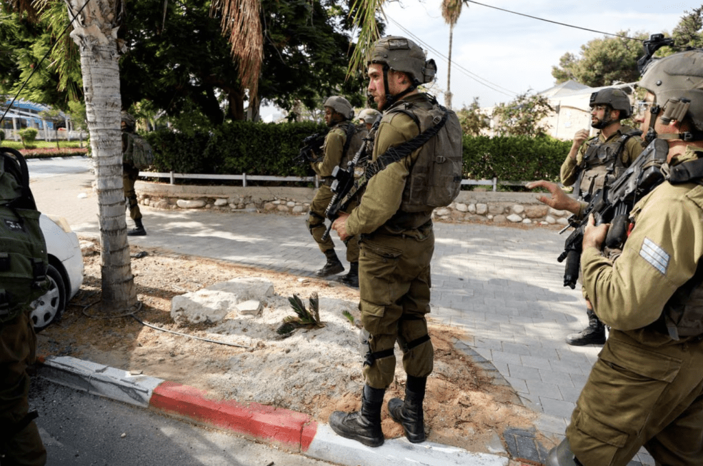 在以色列南部斯德洛特，以色列士兵站在一輛車旁，車上裝有一名男子的屍體，該男子在來自加沙地帶的哈馬斯槍手大規模滲透後被殺。路透社