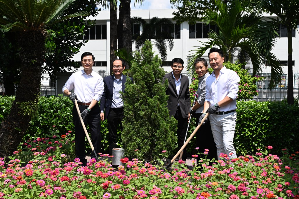 李家超（左一）到访一间总部设于香港的纺织公司并参与植树仪式。