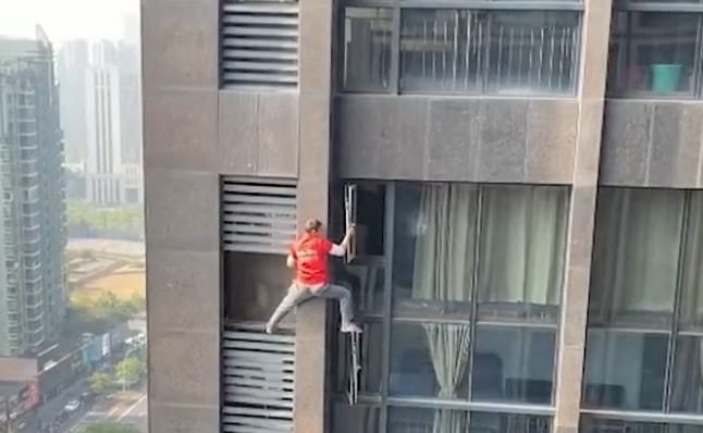 1名身穿工作服的男子在沒有任何安全裝備下，於17樓徒手爬出窗外維修冷氣 。影片截圖