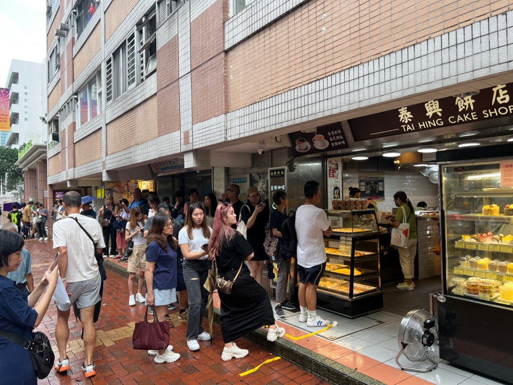 今日間中下起滂沱大雨，下午2時仍有近百人排隊購買「熱香餅漢堡」。林曉敏攝