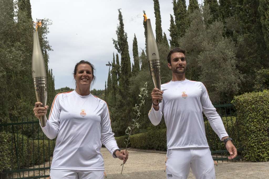 希臘運動員、東京奧運會男子賽艇項目金牌得主斯特凡諾斯·恩圖斯科斯（右）與第二棒火炬手、法國游泳奧運冠軍馬諾杜合影。 新華社