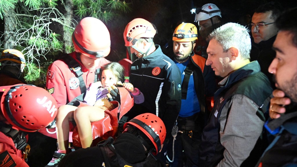 一名小女孩在夜间获救，被救援人员抱起。 路透社