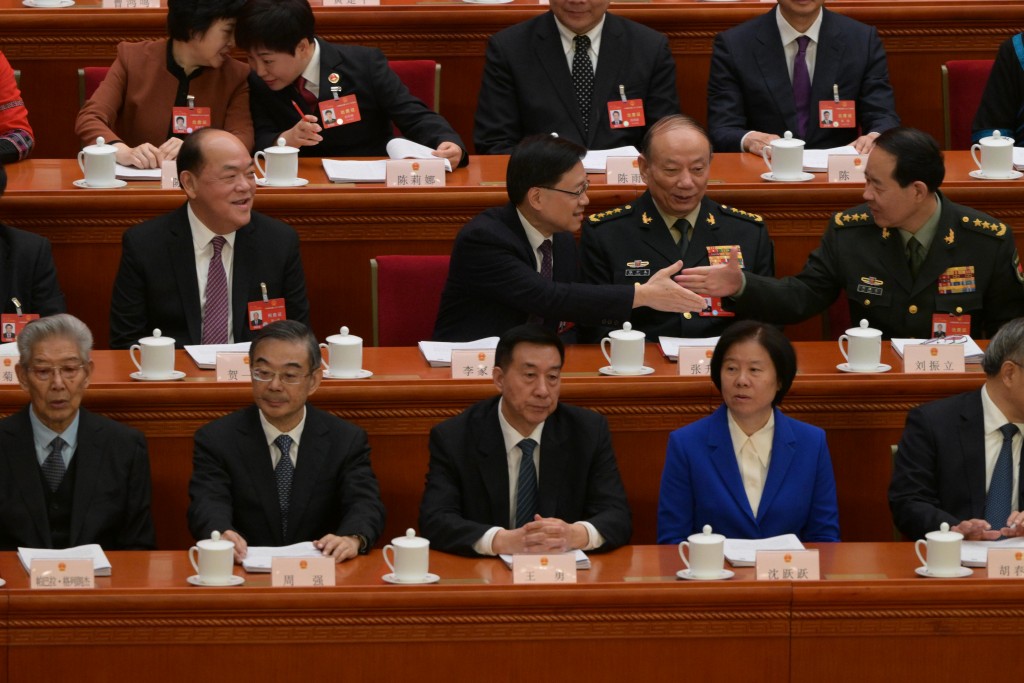坐下之后分别与坐其左手旁的中央军委委员张升民及刘振立握手。苏正谦摄
