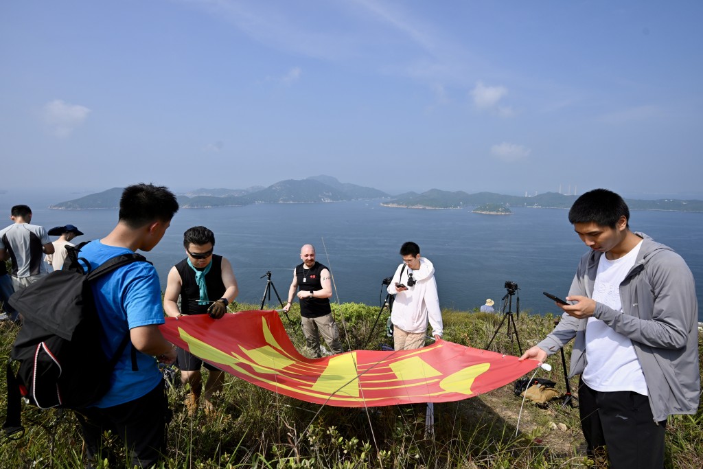 有市民於玉桂山頂上舉起自製的「軍強民樂」旗幟,表示是回應山東艦進港時甲板上的「國安家好」字句。劉駿軒攝 有市民於玉桂山頂上舉起自製的「軍強民樂」旗幟,表示是回應山東艦進港時甲板上的「國安家好」字句。劉駿軒攝