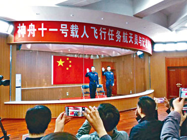 景海鹏(左)与陈冬两名神舟十一号航天员，在记者会上向传媒挥手。