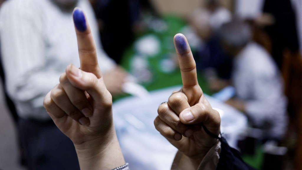 伊朗選民展示沾上墨水的手指，證明已投票。（路透社）
