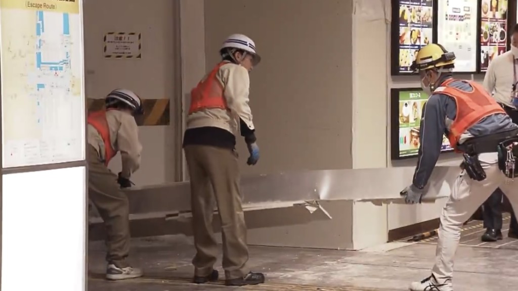 工作人員將掉落的天花面板抬走。 NHK截圖 工作人員將掉落的天花面板抬走。 NHK截圖