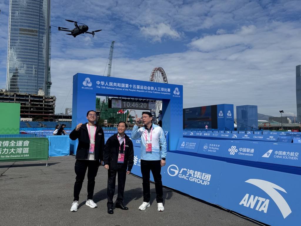 黃志光（中）今日到鐵人三項比賽場地，視察無人機技術在賽事仲裁工作中的應用情況。