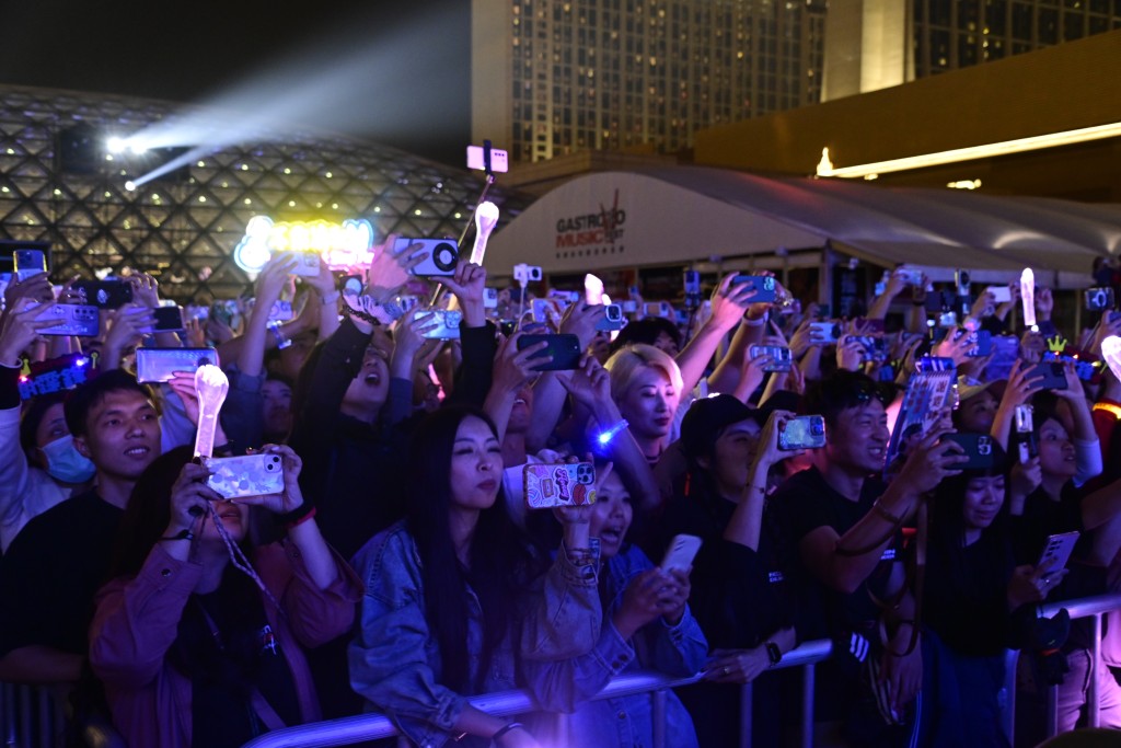 有粉丝站在櫈上用手机拍摄霆锋台上的演出片段。