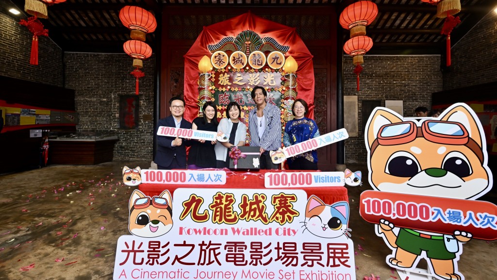 康文署助理署長（康樂事務）馮妙玲（右一）、文創產業助理專員兼香港電影發展局秘書長麥聖希（左一）和《九龍城寨之圍城》演員張文傑（右二），向第10萬名參觀者（中）送上紀念品。政府新聞處