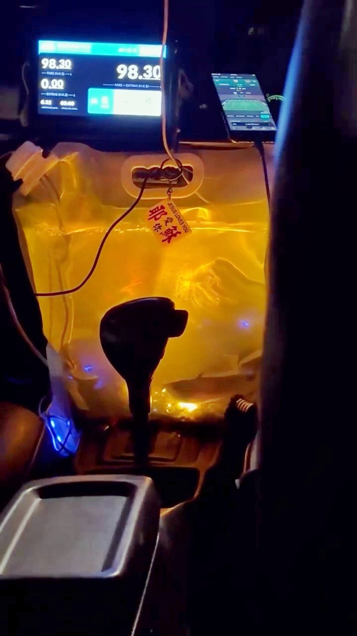 片中的天色已黑，從後座拍攝的短片見到，膠 袋魚缸掛於咪錶下，膠袋左上角的入口插有疑 似氣泵裝置。透過泛黃燈光，見到膠袋內的水 隨行車時上下蕩漾，並見到銀龍魚在缸底暢泳。Threads截圖