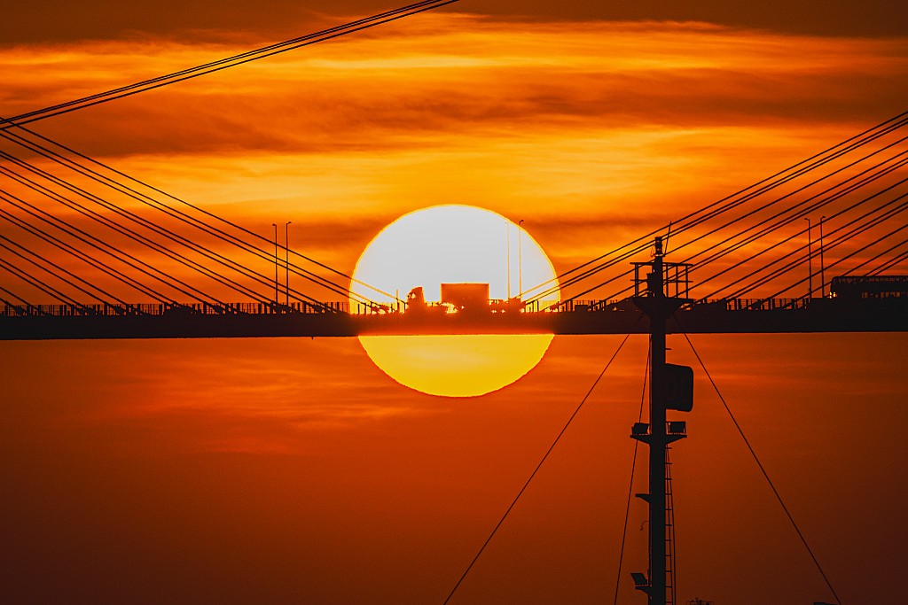 落日躲於汀九橋後，剪影著駛過橋上貨車的輪廓。圖片授權：Angus Chan