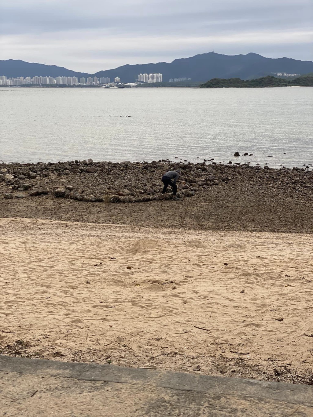 一名中年男子慢慢将大石砌出一个倒心形。fb「乌溪沙石滩海岸关注组」图片