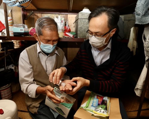 聶德權(右)向獨居長者送贈口罩、酒精搓手液和清潔用品。 政府圖片