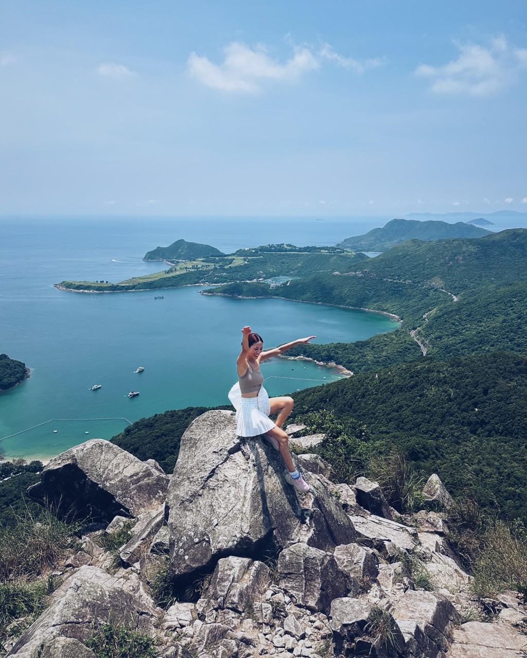 陈凯琳站在山峰嶙峋的石尖上，举起双手拍照。