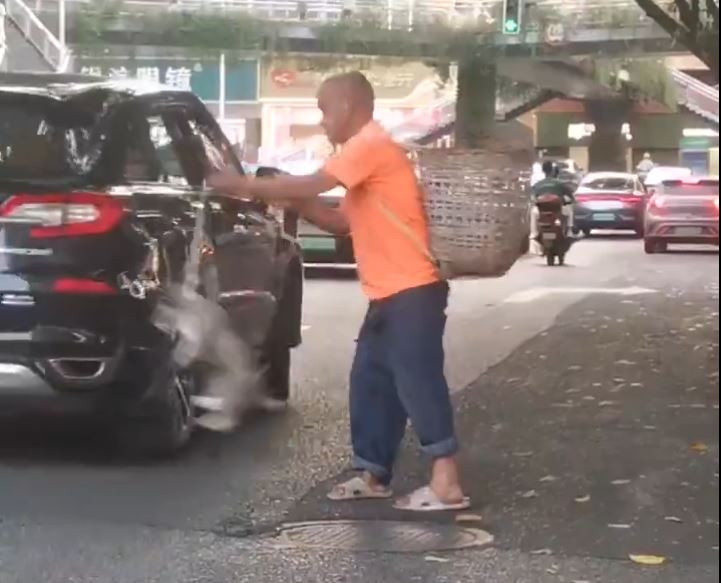 四川街頭有中年漢疑為碰瓷，將小狗掟向汽車車頭。微博