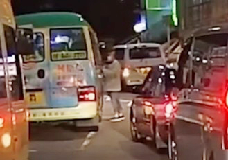 一位阿叔站在馬路中央與小巴司機隔窗對罵，影片未有聲音，未知兩人衝突原因。