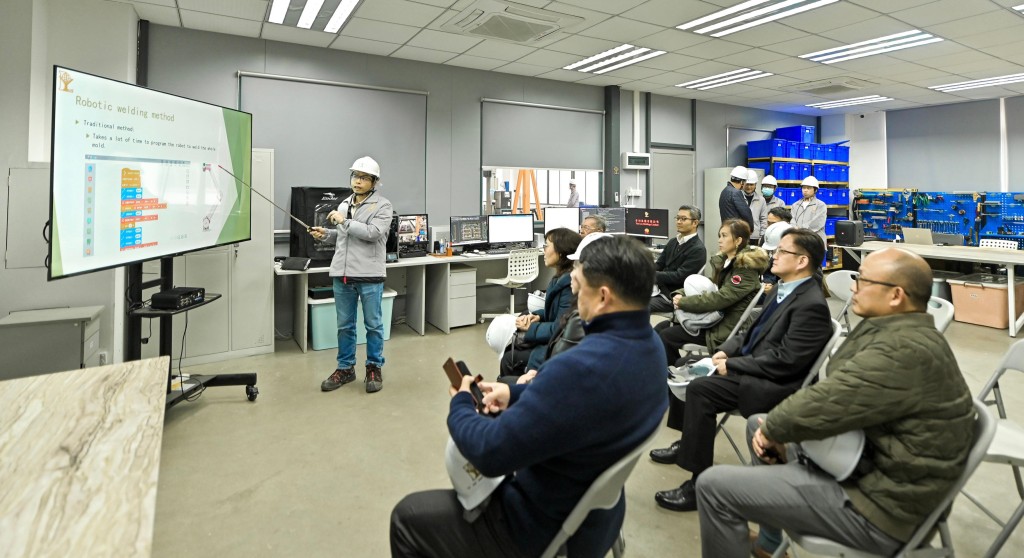 甯漢豪(前排右三)周一(22日)到訪有利華建築預製件有限公司，聽取工作人員介紹自動化焊接工序。政府新聞處圖片