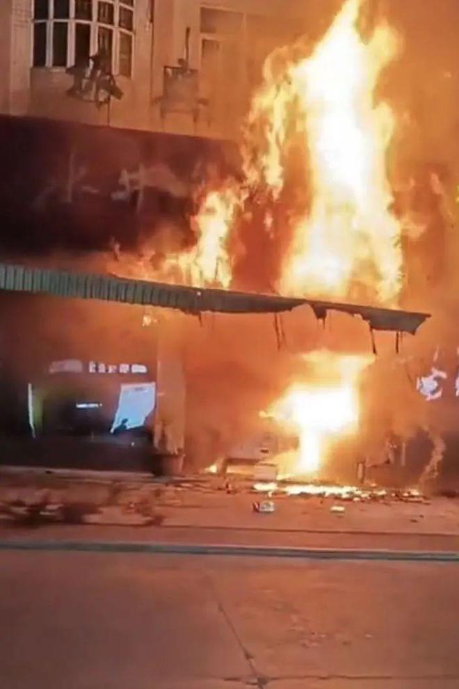白色私家车撞入商店后迅即引发大火，周边商店人员欲救无从。影片截图