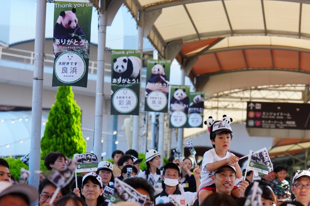 工作人員與當地民眾在日本和歌山縣冒險世界遊樂園外目送運輸大熊貓的運輸車離開。 新華社