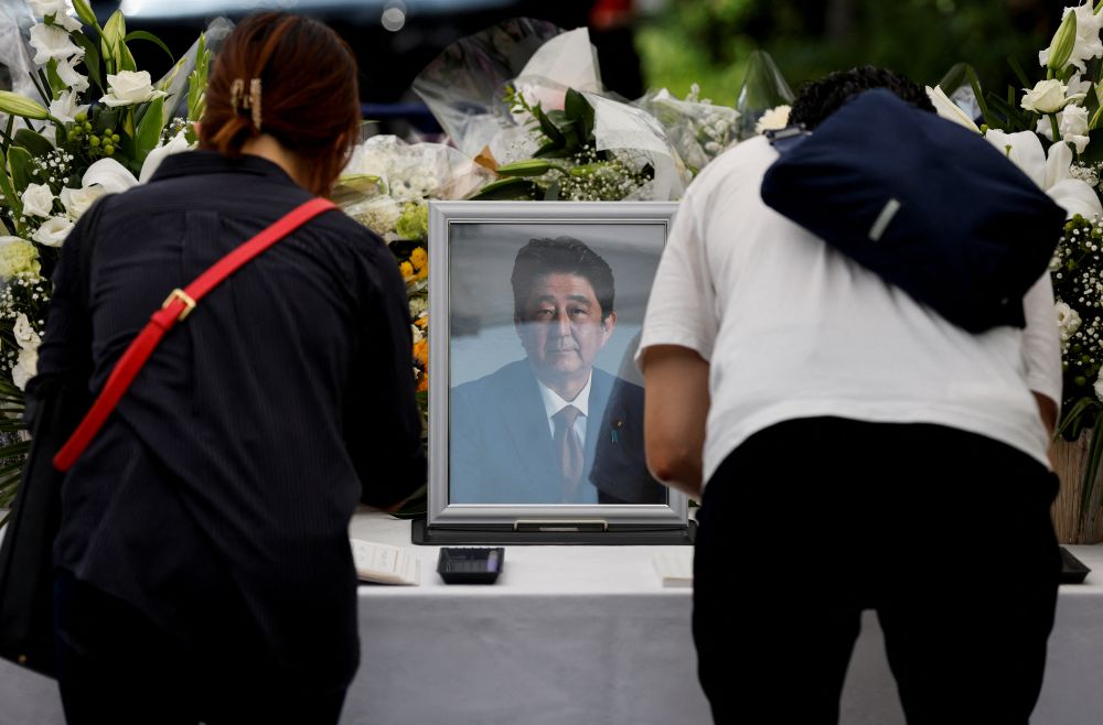 日本东京自民党总部的祭坛上，哀悼者在已故日本前首相安倍晋三的肖像照片前鞠躬。路透社图片