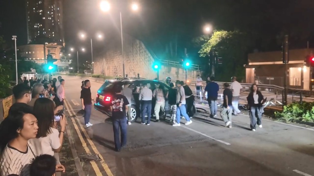 大約有30名熱心市民與警員合力將私家車推回慢線,讓後方的車輛可以通過。fb「屯門公路塞車關注組」Cherubim Cole片段截圖 大約有30名熱心市民與警員合力將私家車推回慢線,讓後方的車輛可以通過。fb「屯門公路塞車關注組」Cherubim Cole片段截圖
