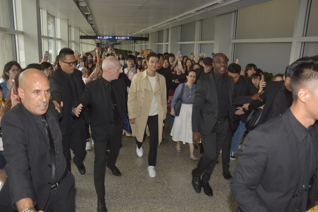 始源在約10名保安及工作人員開路下,現身機場。