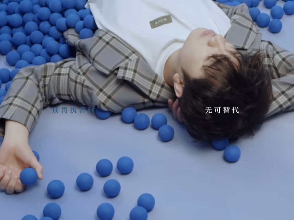 王祖藍躺在地上，身旁有一堆小丑常用的藍色小球。