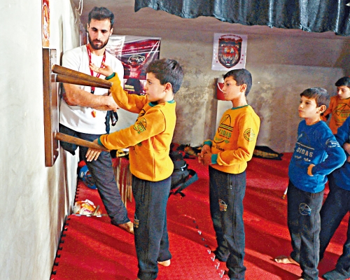 因伤截肢的功夫教练欧斯曼（左）指导学生武术。