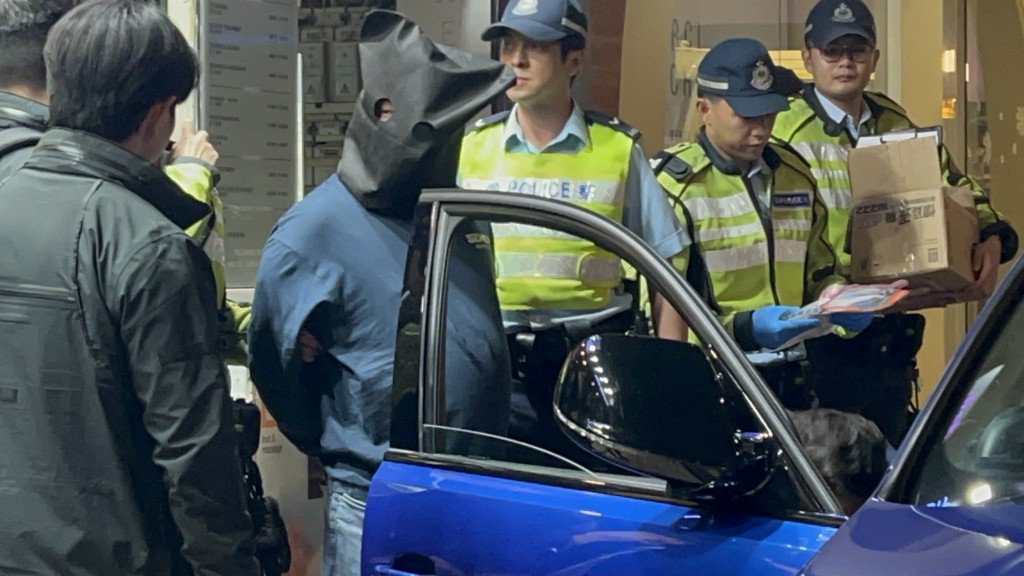 司機黑布蒙頭，雙手鎖上手銬。楊偉亨攝