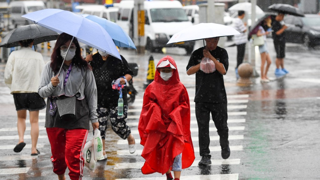 在北京市朝陽區行人冒雨行走在路上。新華社