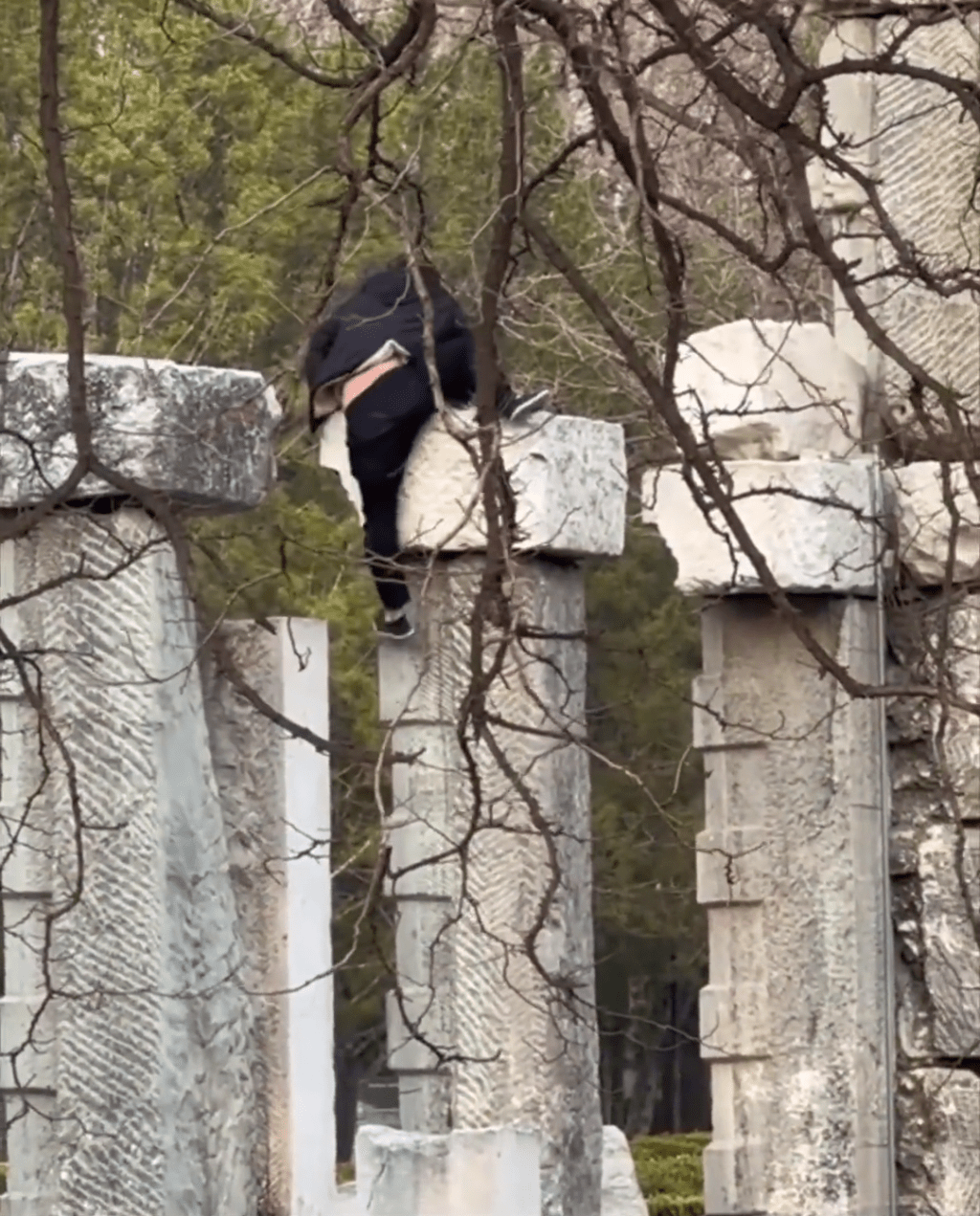 男子在攀爬遺址建築，狀甚吃力，險象環生。