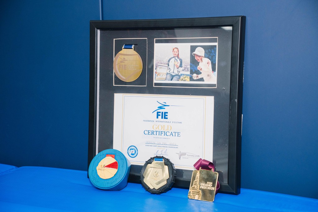 佘佘嗲哋細心將女兒2018年奪得的世少金牌及證書、領獎照片鑲入相框內。汪旭峰攝