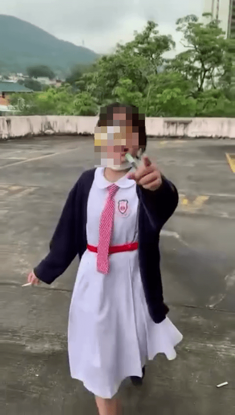 吸煙女生發現被友人拍攝後隨即用手指向拍片者，示意對方停止拍攝。網圖